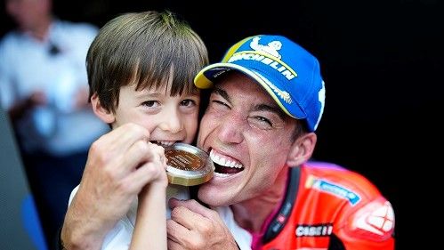 息子とともにスプリントレース優勝の金メダルをかじるパフォーマンスを見せるアレイシ・エスパルガロ選手（写真：motogp）