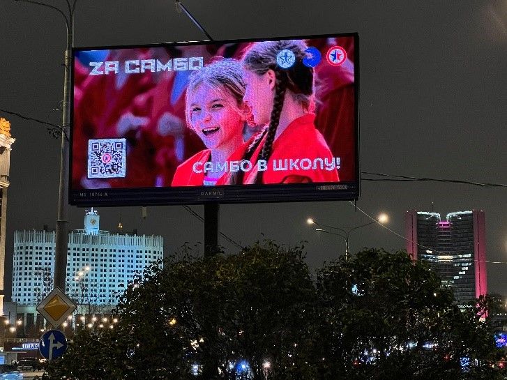 「学校でサンボをやろう！」の電子広告。背後のビルには「Z」