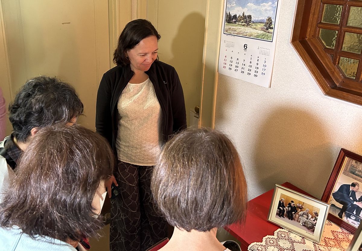 国王来日時の写真について見学者に説明するロクサンヌ・ドゥ・ビルデルリング前大使（井上撮影）