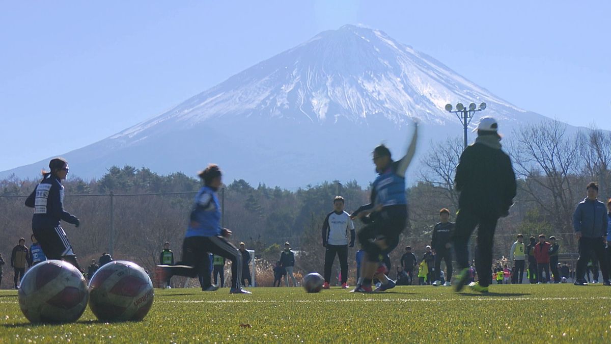 初冬のピッチを見守る雪化粧の富士山