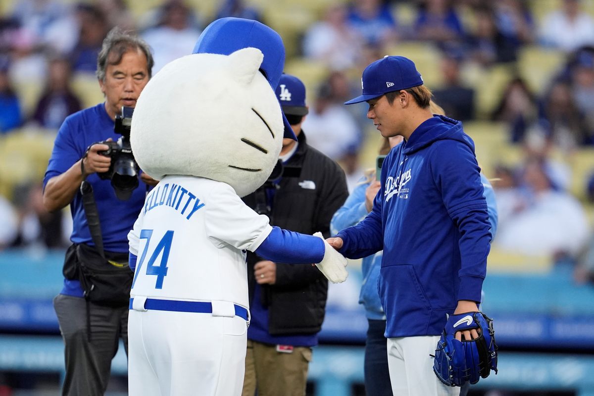 握手するハローキティ(左)と始球式のキャッチャーを務めた山本由伸投手(写真:AP/アフロ)